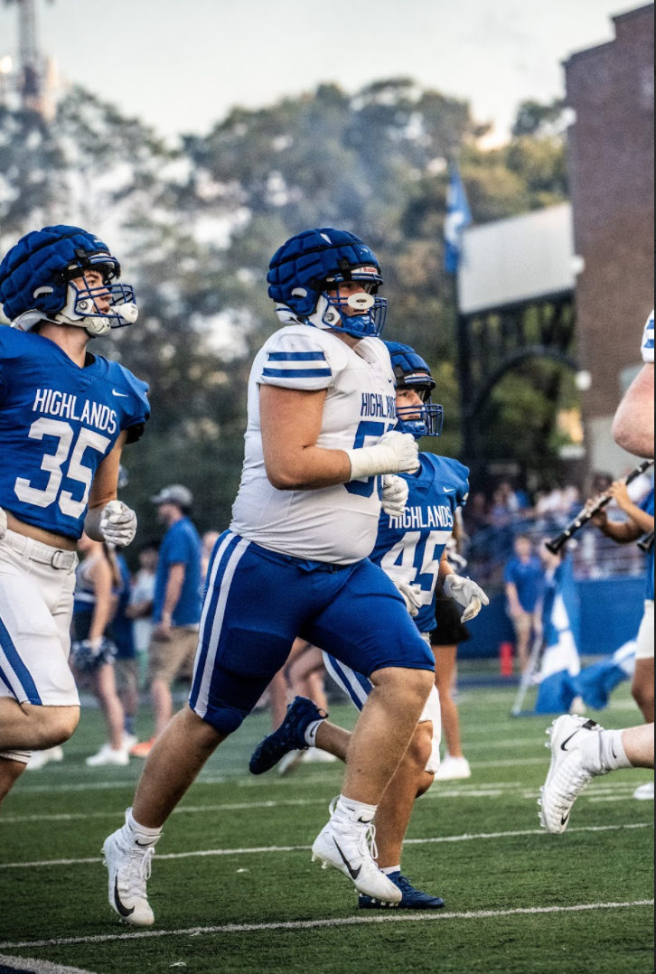 Max Merz (11) runs out on the field after breaking the poster. Merz said, "I felt amazing being the first teammate to break through the poster our cheerleaders made for us." 